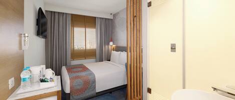 A hotel room with a bed, bedside table, and a bathroom.