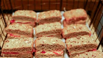 A display of square-shaped baked goods with visible nuts and a pink filling, arranged in a wire basket.