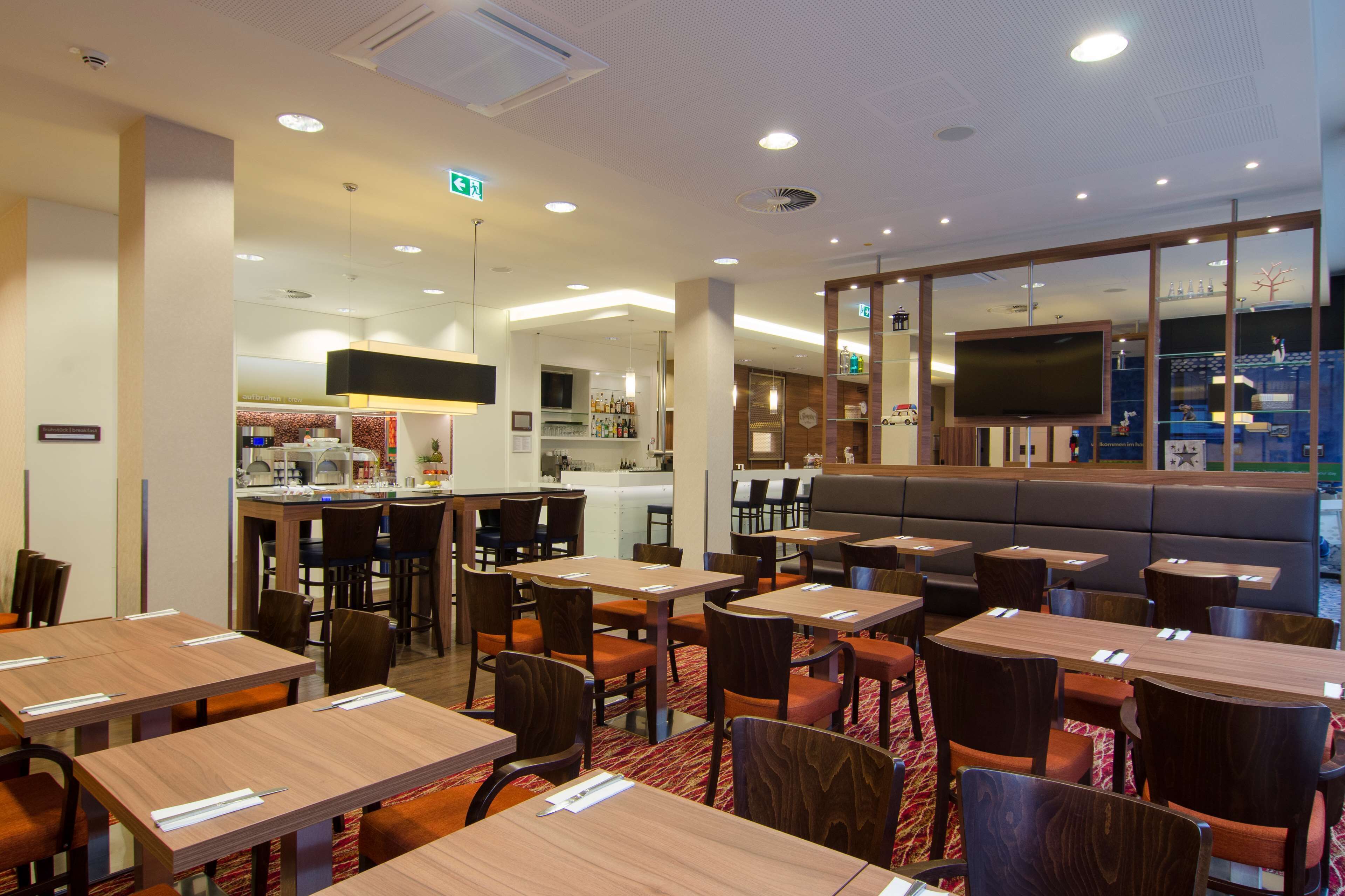 A hotel lobby with multiple seating areas, a bar, and a television screen.