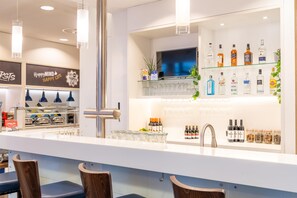A bar area with a modern design, including a TV, a variety of liquor bottles, and a glass display. - Hampton by Hilton Nuremberg City Centre (Nuremberg)