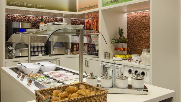 Zona de bufé con diversas opciones de comida, como pan, frutas y salsas.