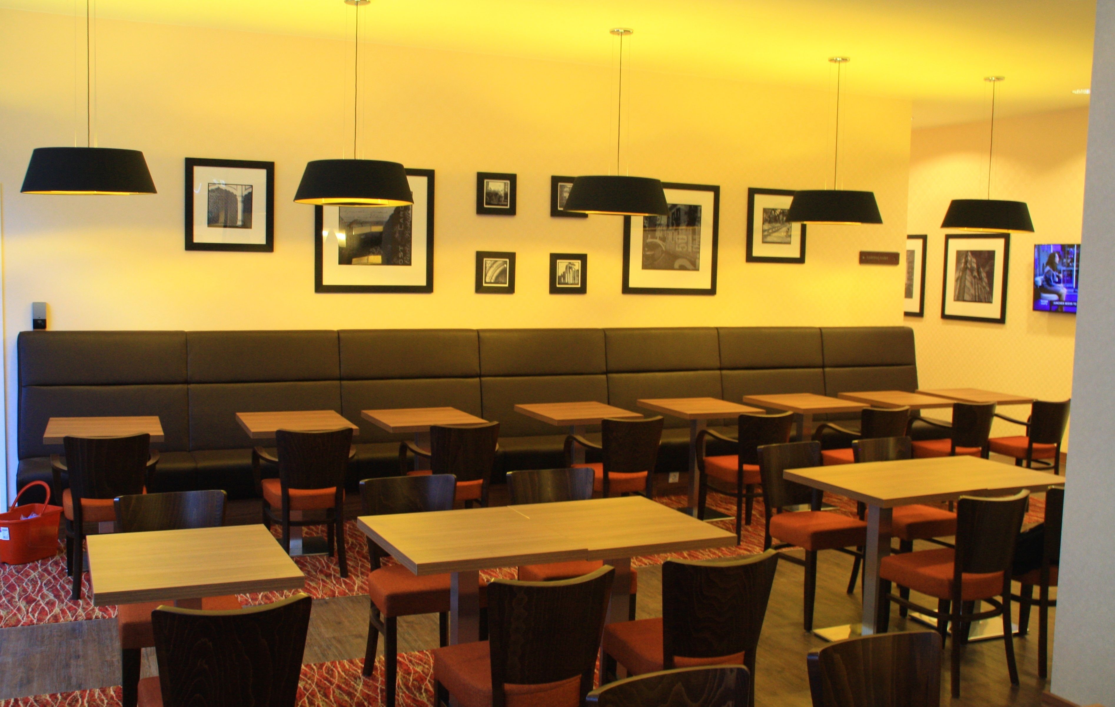 A restaurant with booths and tables, framed pictures on the wall, and pendant lighting.