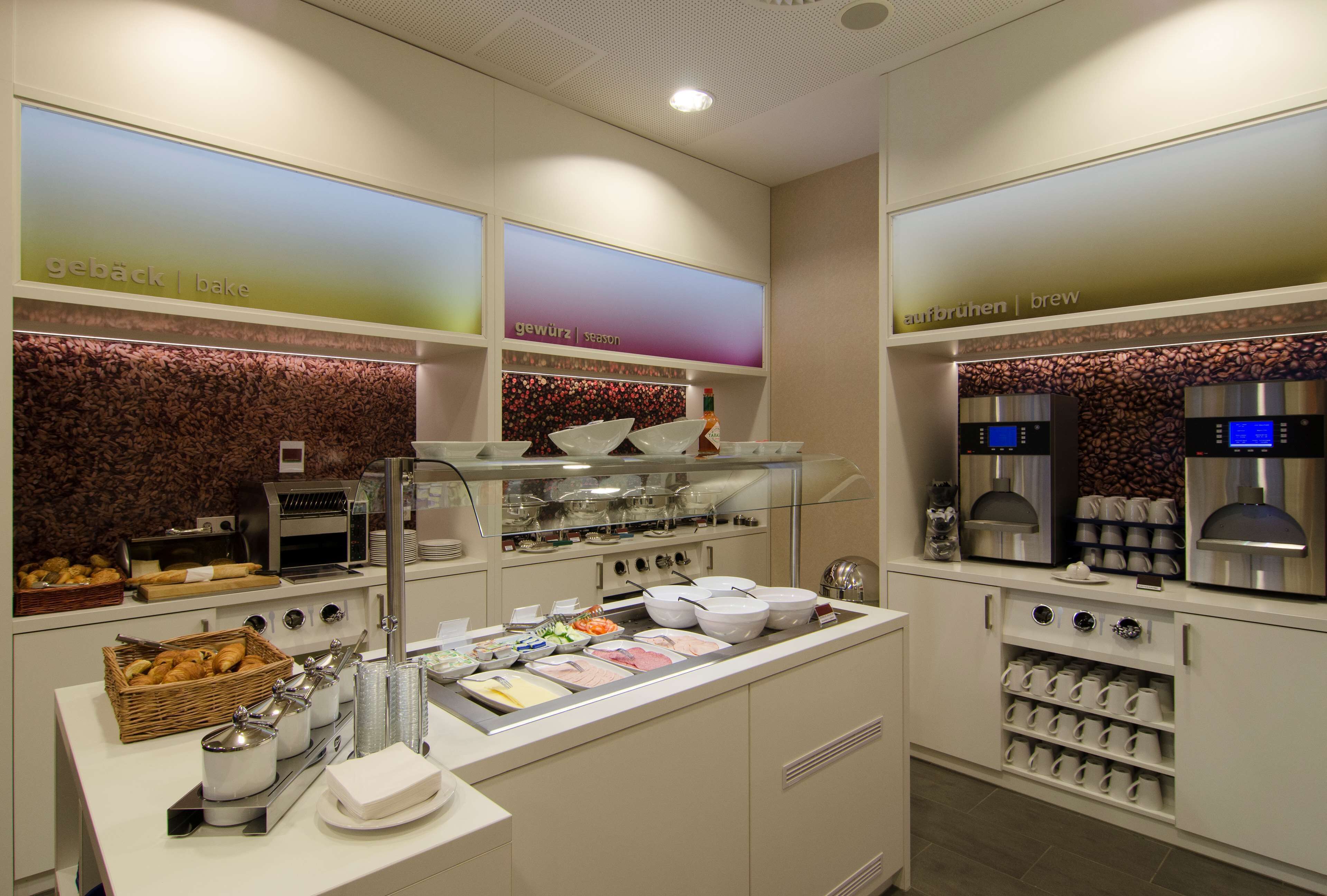 Zona de desayuno tipo buffet con diversas opciones de comida, una estación de café y una selección de tazas y cuencos.