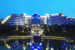 Un hotel grande con varios pisos, un atrio central y una masa de agua al frente.