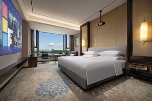 Un moderno cuarto de hotel con una cama grande, un escritorio y vista a la ciudad.
