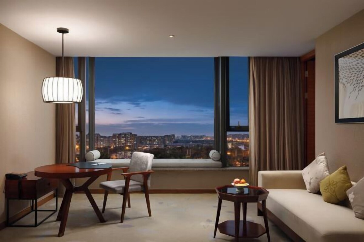 Una habitación de hotel moderna con vistas a la ciudad, un área de comedor y un rincón de estar.