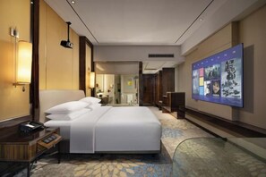 Habitación de hotel con una cama grande, mesitas de noche, un escritorio y un cartel grande en la pared.