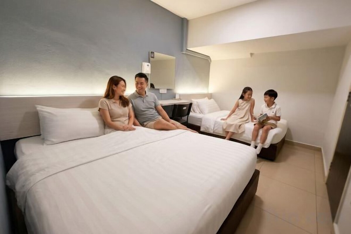 A hotel room with a large bed, bedside tables, and a mirror on the wall.