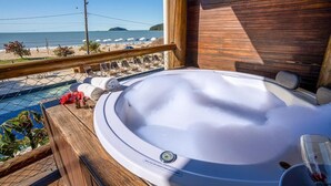 Una terraza de madera con jacuzzi con vista a una playa.