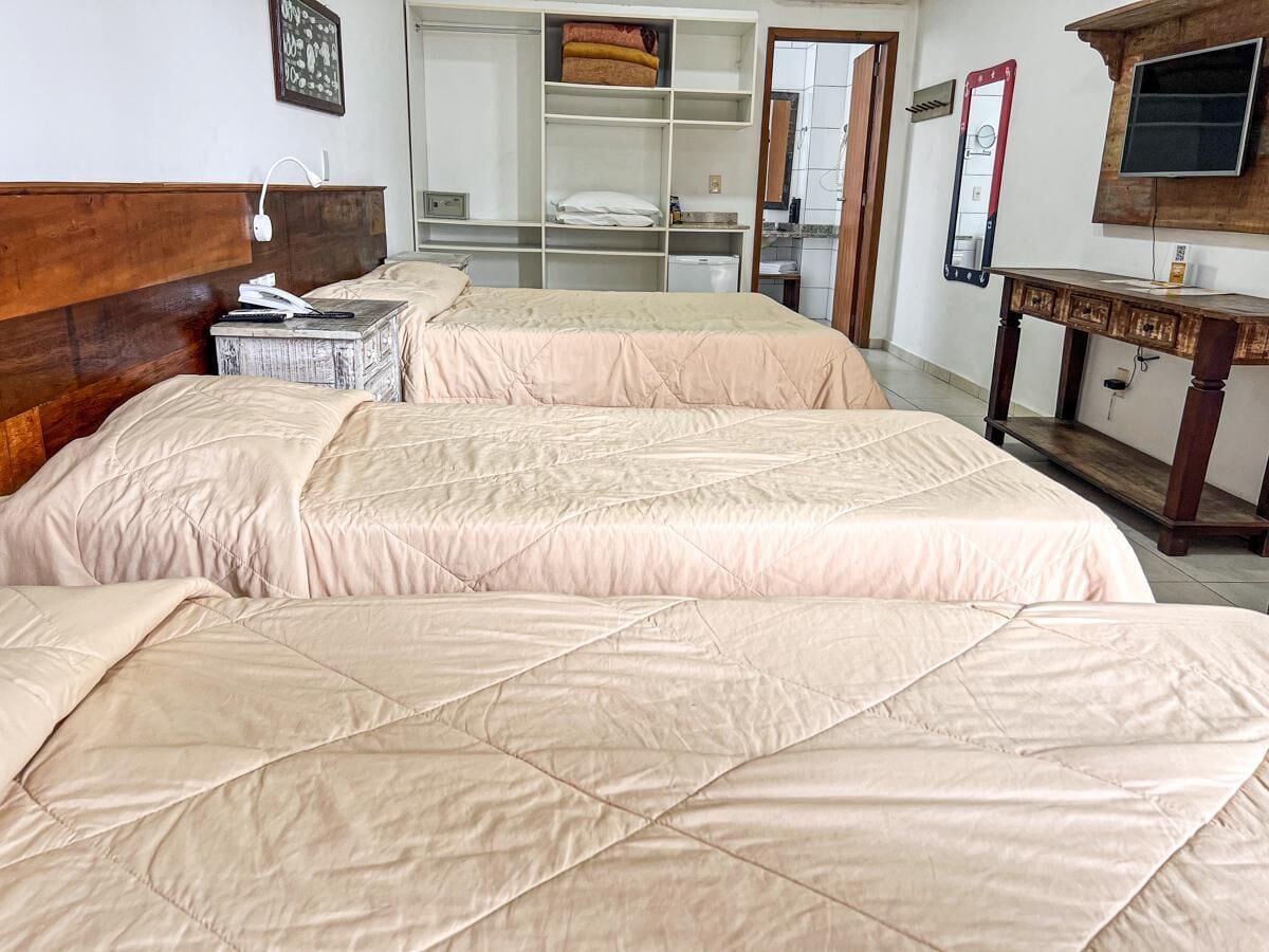 A hotel room with two beds, a wooden headboard, a desk with a TV, and a mirror.