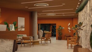 Un vestíbulo moderno con muebles de madera, una recepción y una gran planta en maceta.