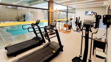 A gym with treadmills, exercise machines, a pool, and a wooden ladder.