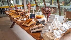 Una mesa de buffet con diversos alimentos, como pasteles, pan y frascos con conservas.