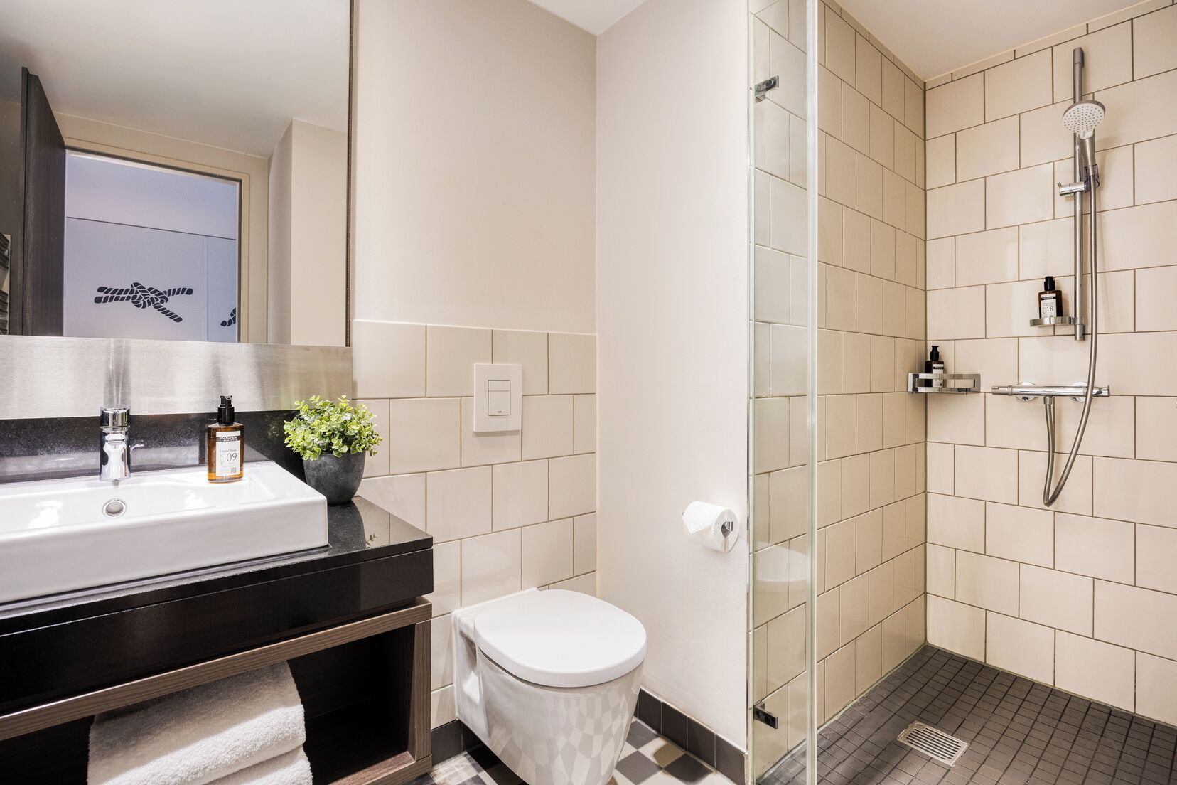 Une salle de bain moderne équipée d’un lavabo, de toilettes et d’une douche.