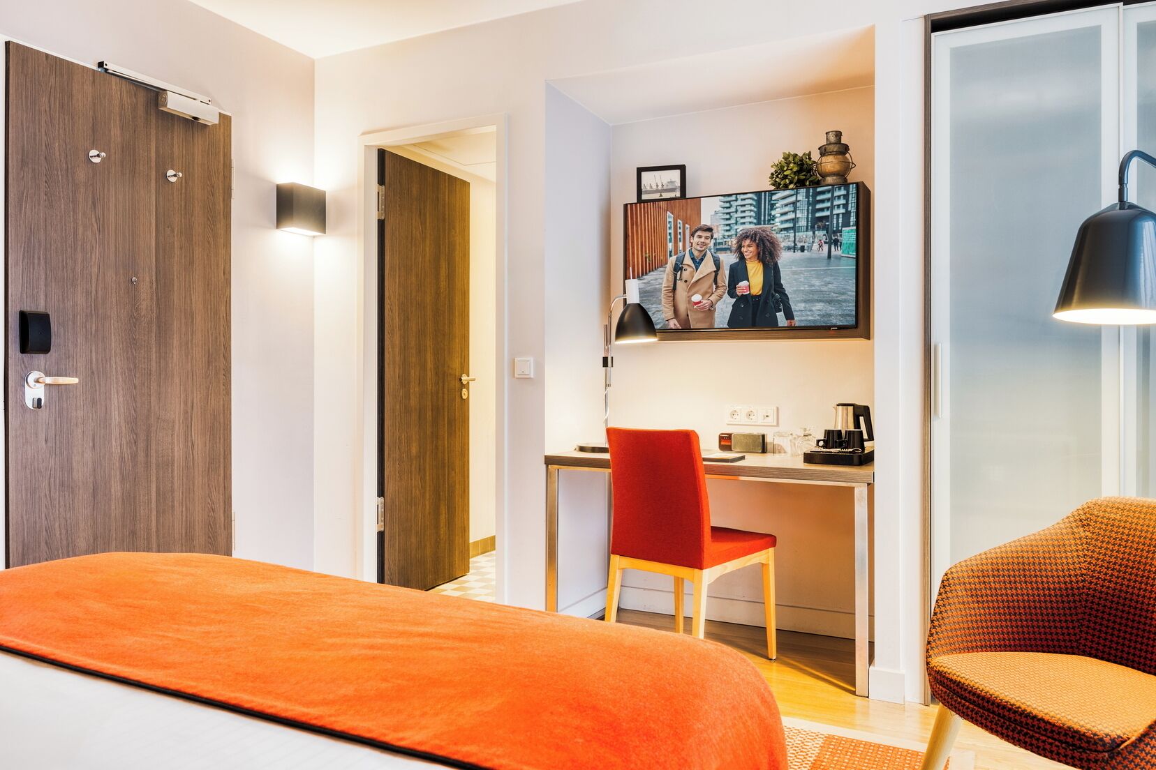 Ein Hotelzimmer mit Bett, Schreibtisch mit Stuhl, Fernseher und Kaffeemaschine.