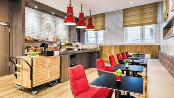 A modern restaurant with a wooden counter, red chairs, black tables, and pendant lighting.