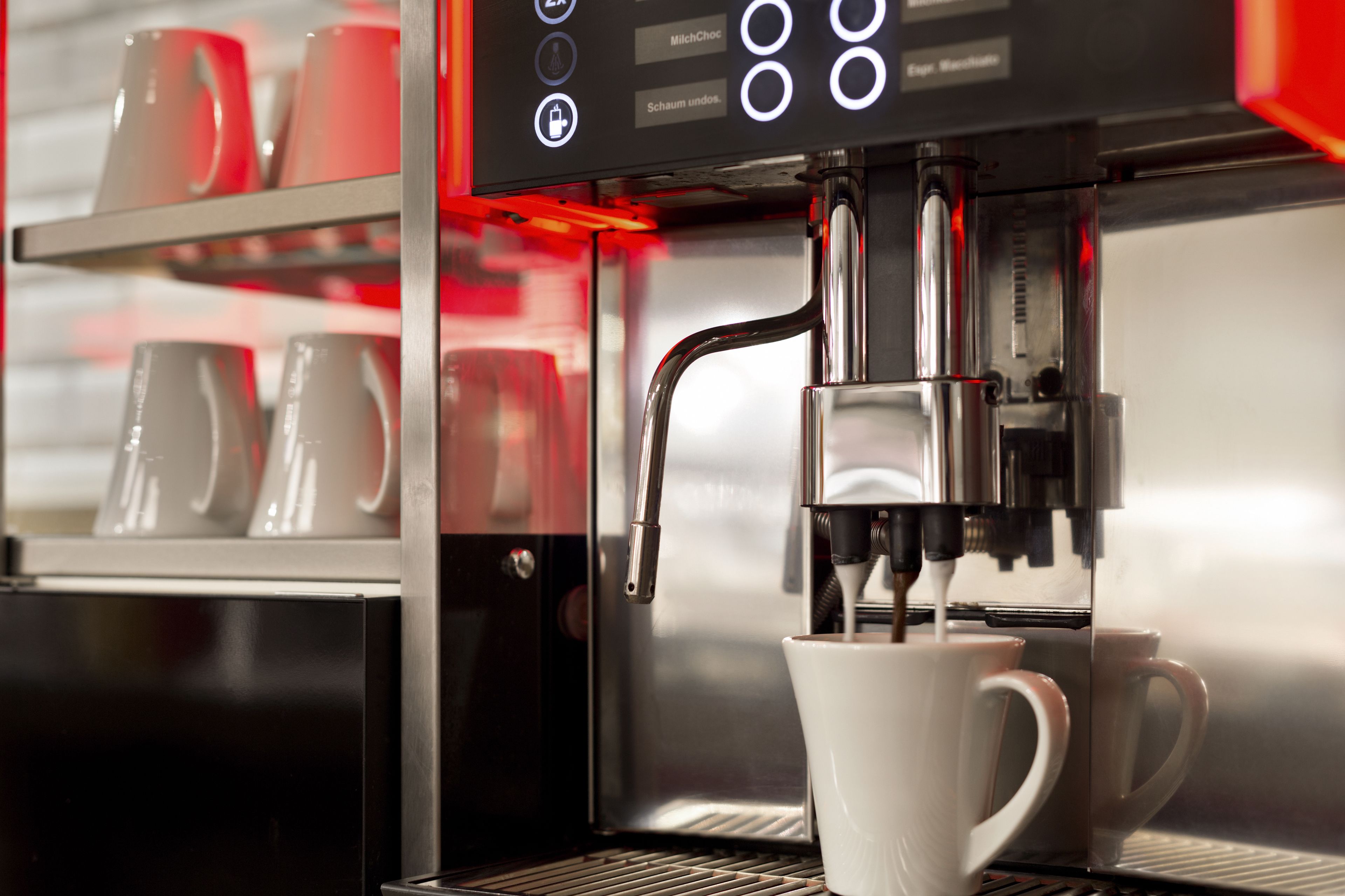 A coffee machine with a digital display and a cup of coffee being dispensed.