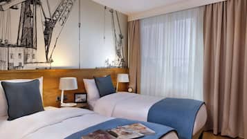 A hotel room with two beds, a large window with curtains, a wall mural, and a clock on the nightstand.