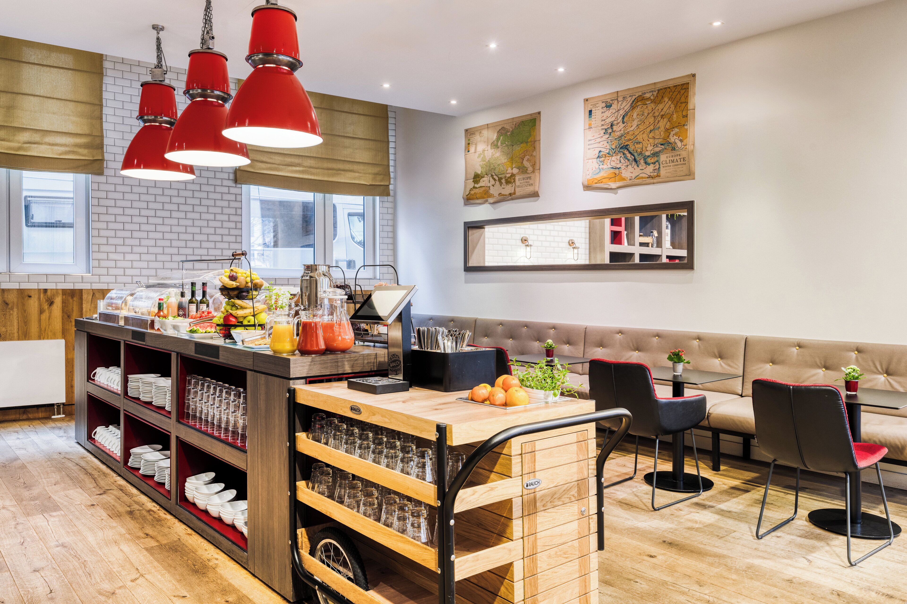A modern kitchen with a wooden island, red pendant lights, and a seating area with a sofa and chairs.
