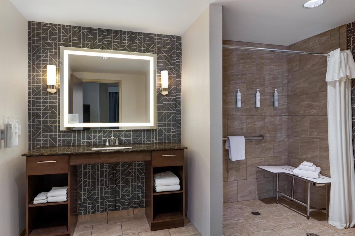 A modern bathroom with a large mirror, a vanity with a sink, and a shower area with a glass door.