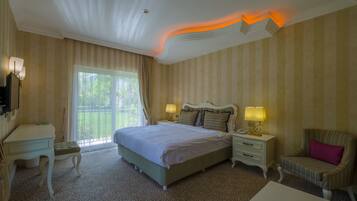 A hotel room with a large bed, a desk, a chair, and a small table.
