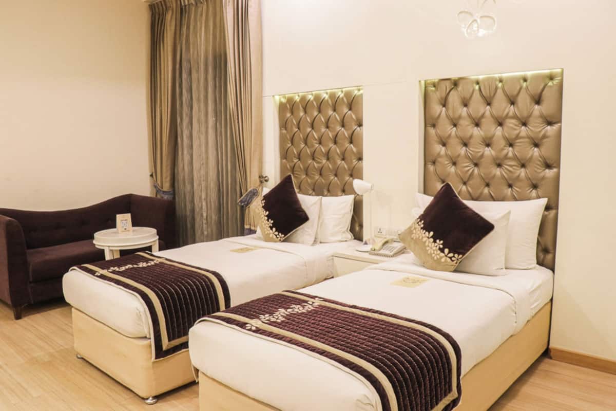 Une chambre d’hôtel avec deux lits, un canapé, une petite table et une lampe.