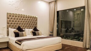 A bedroom with a large bed, a tufted headboard, and a view of a garden through a glass door. - Eternity (New Delhi)