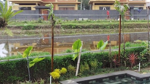 A two-story building with a balcony, surrounded by a water body and greenery. - Villa Kemuning Ubud (Tegallalang)