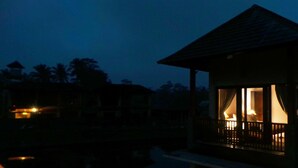 A small, single-story building with a balcony, illuminated by interior lights. - Villa Kemuning Ubud (Tegallalang)