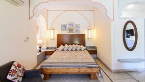 Une chambre à coucher avec un lit en bois, une table de chevet, une lampe, un miroir et un mur orné de tableaux.
