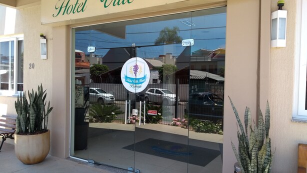 La entrada del Hotel Ville House, con una puerta de cristal, un cartel que indica 'Hotel Ville House Premium' y plantas en macetas en el exterior.
