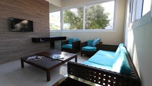 Una sala de estar moderna con un sofá, dos sillones, una mesa de centro y un televisor de pantalla plana montado en la pared.