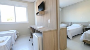 Habitación de hotel con dos camas, un escritorio, un televisor y una ventana.