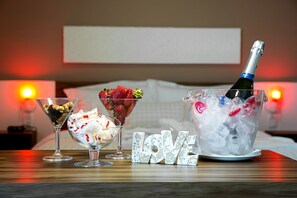 A table with three dessert glasses, a bottle of champagne in a bucket, and a 'LOVE' sign.