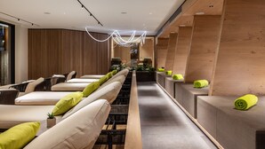 Ein moderner Wellnessbereich mit einer langen Bank, gepolsterten Sitzgelegenheiten und Holzelementen.