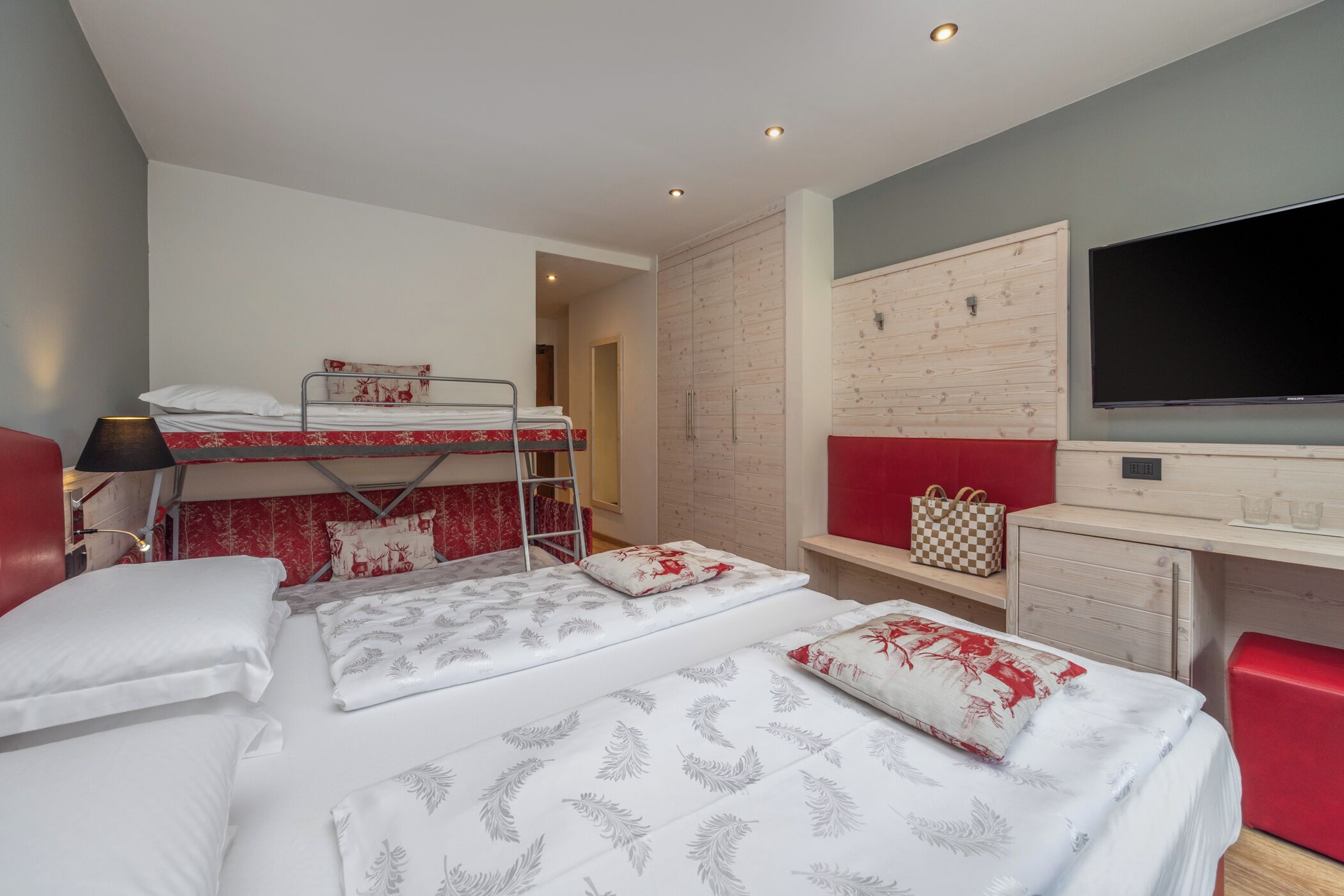 Une chambre d’hôtel avec des lits superposés, un bureau, une télévision et une armoire.