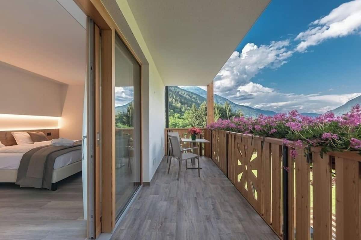 A balcony with a wooden floor, a bed with a headboard, and a table with chairs.