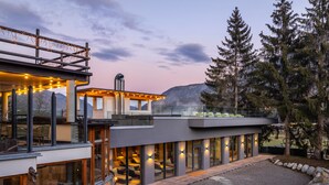 Ein modernes, mehrgeschossiges Haus mit großen Fenstern, einem Whirlpool und einer Terrassenfläche.