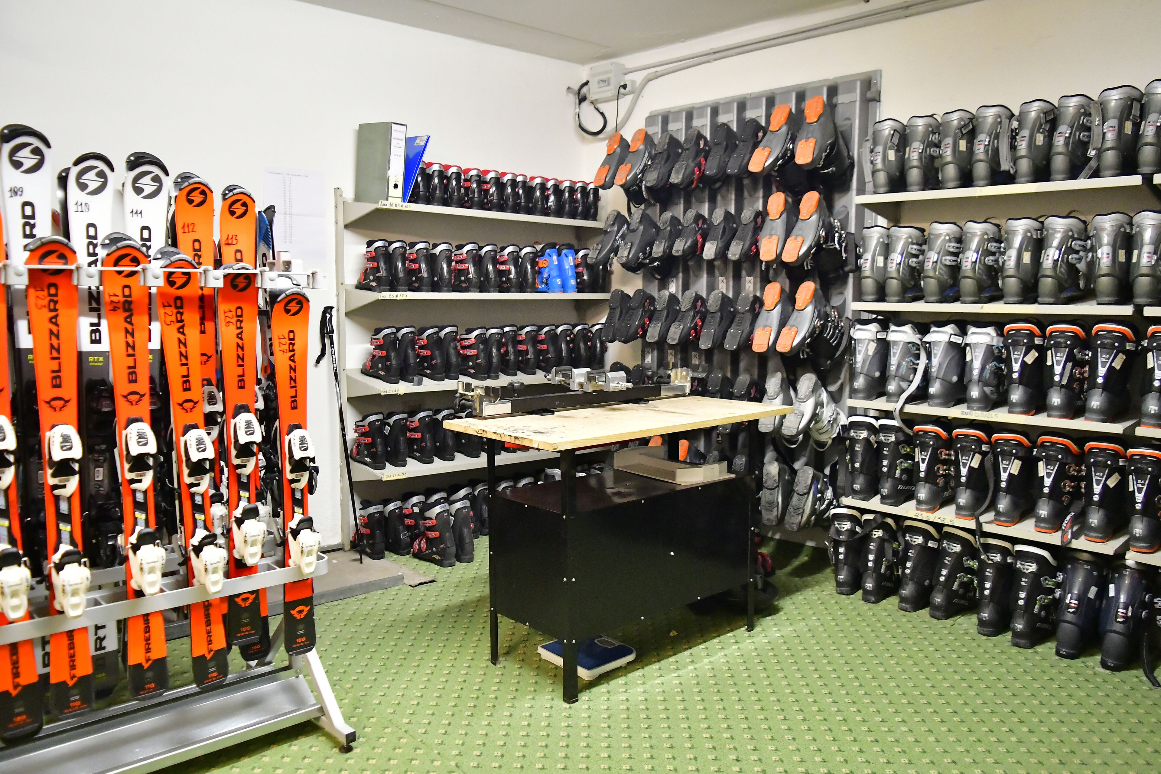 Una tienda de equipo de esquí con estantes llenos de esquíes, botas y cascos.