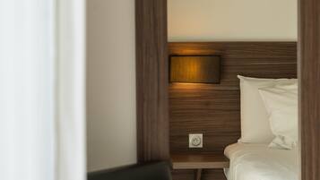 A hotel room with a wooden headboard, a bedside table, a lamp, and a bed.