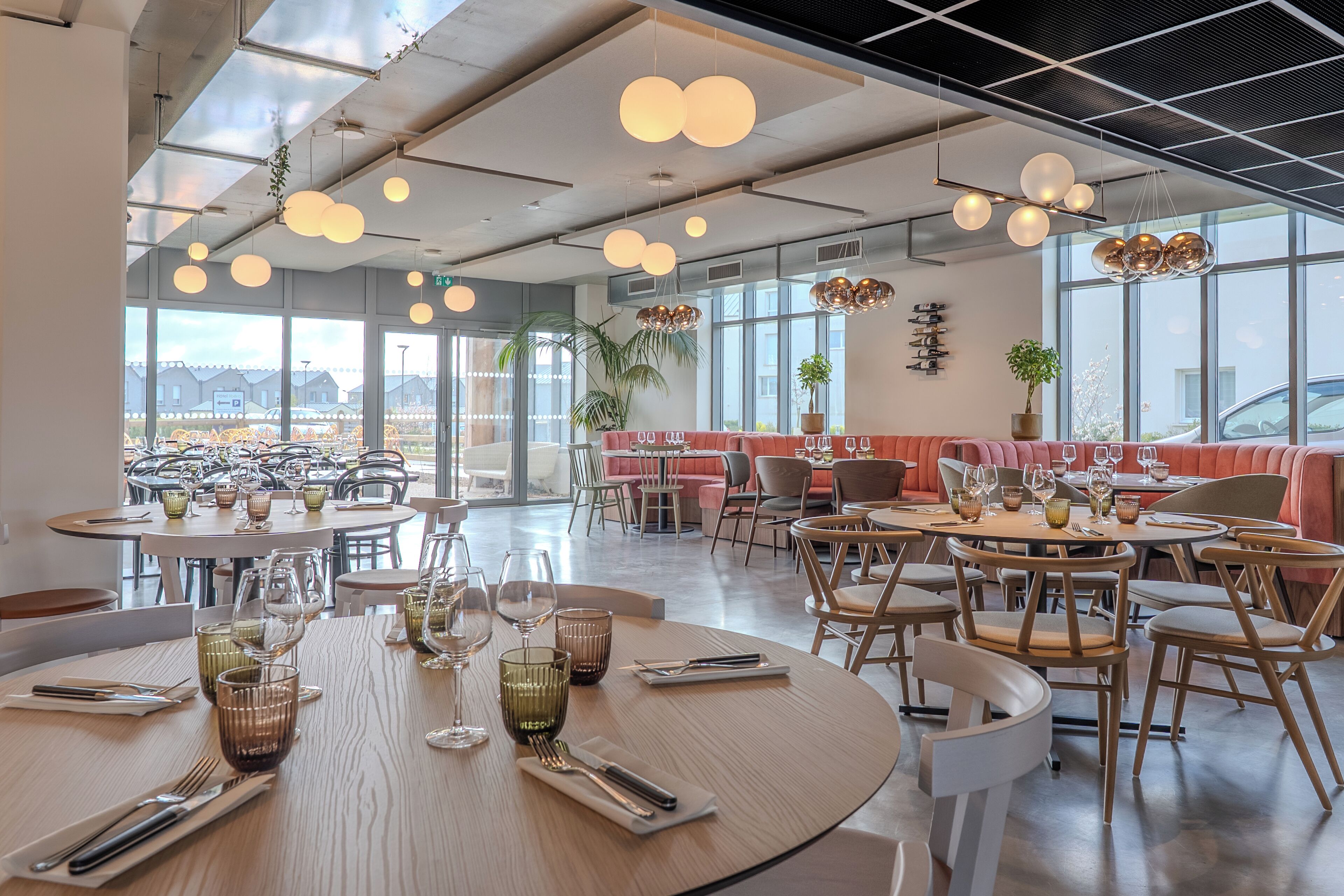 A modern restaurant with round tables, chairs, and hanging spherical lights.