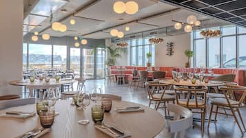 A modern restaurant with round tables, chairs, and hanging spherical lights.