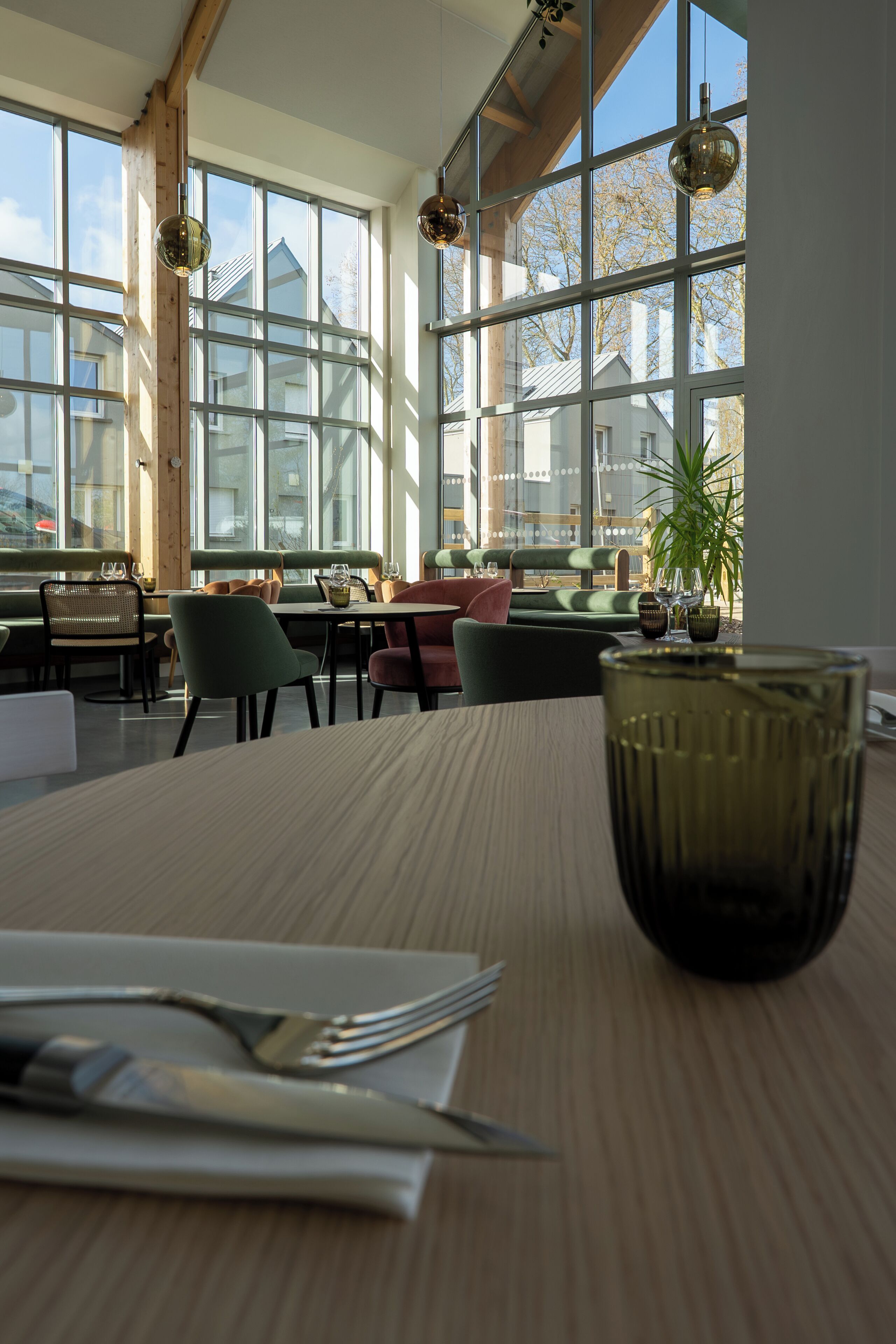 A restaurant interior with large windows, wooden beams, and a table set for dining.