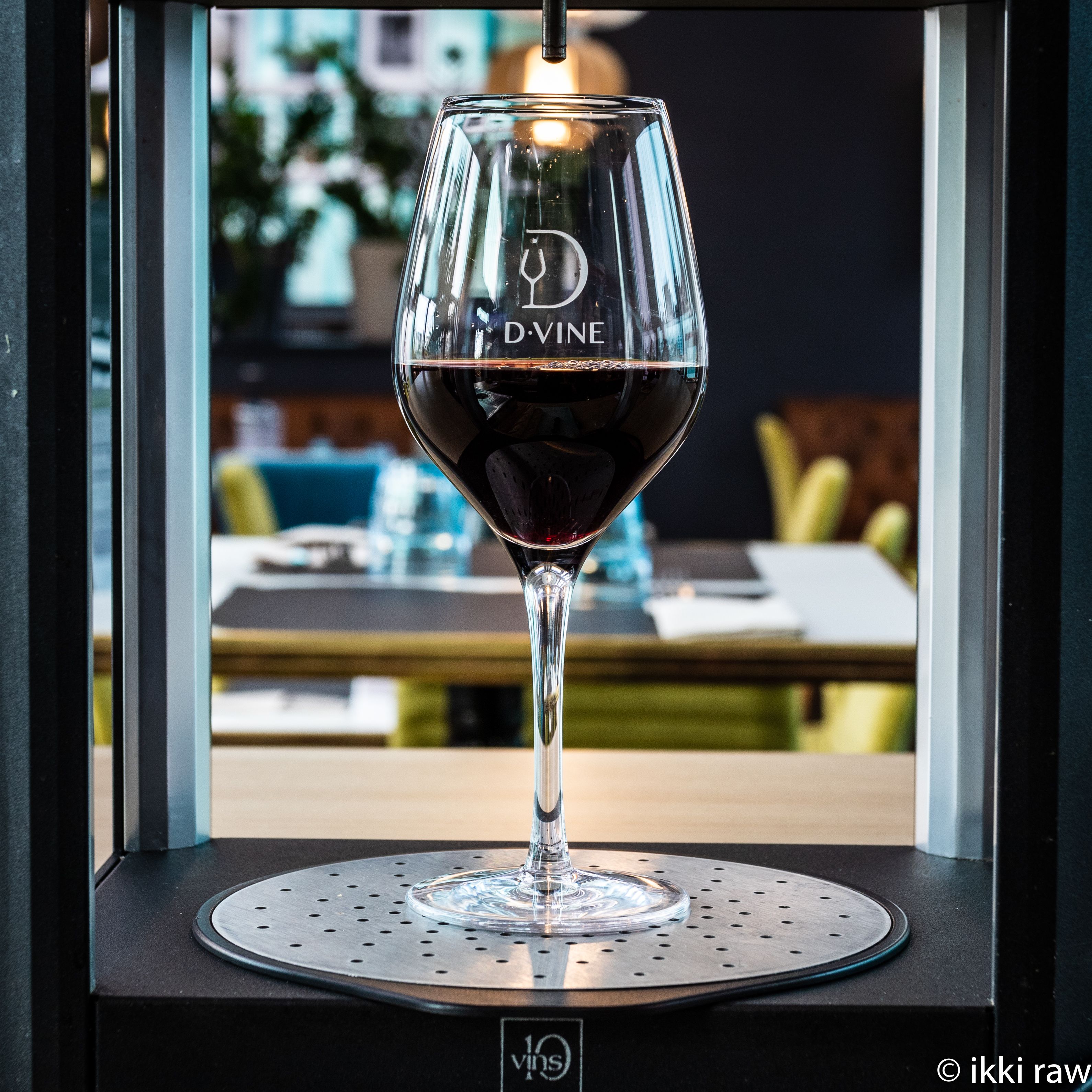 A wine glass with the inscription "D.VINE" on a table with a perforated coaster.
