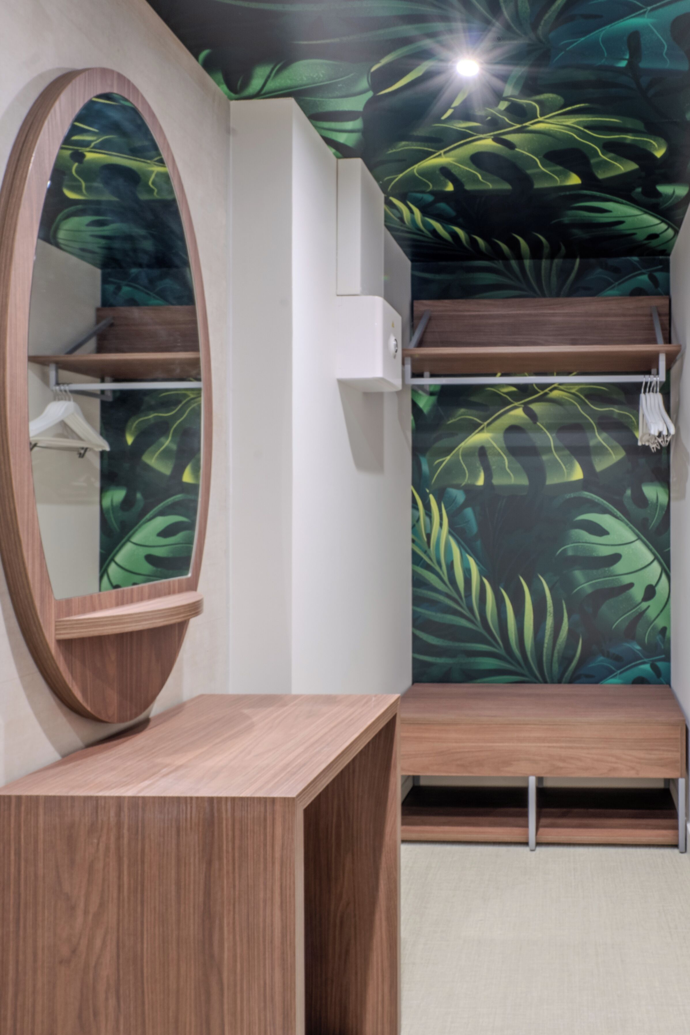 Un bagno con un mobile contenitore in legno, uno specchio, un portascopevoli e un soffitto decorato con un motivo a foglia.