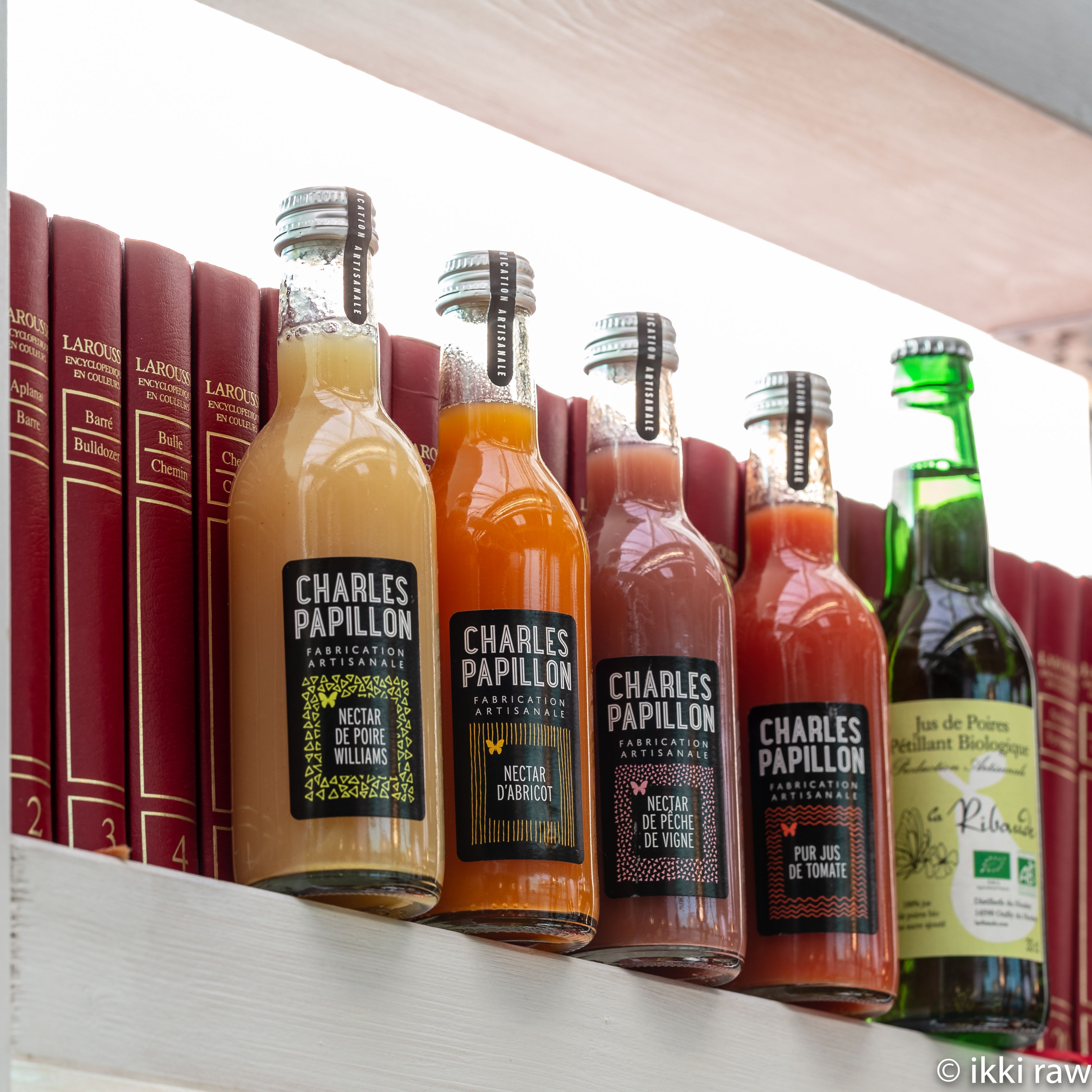 A shelf with books and bottles of Charles Papillon brand beverages.