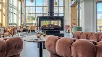 Cómoda zona de estar con sofás mullidos y una mesa dispuesta para comer, con vista a una chimenea moderna.