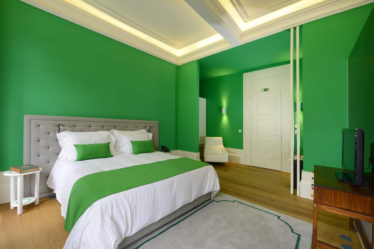 Een slaapkamer met een groot bed, nachtkastje, stoel en televisie.