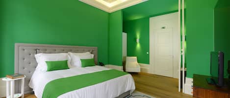 A bedroom with a large bed, a bedside table, a chair, and a television.
