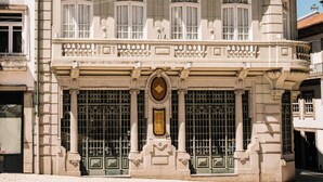 Ein mehrgeschossiges Gebäude mit einem Balkon, aufwendigen architektonischen Details und einem auffälligen Eingang mit einer verzierten Tür.